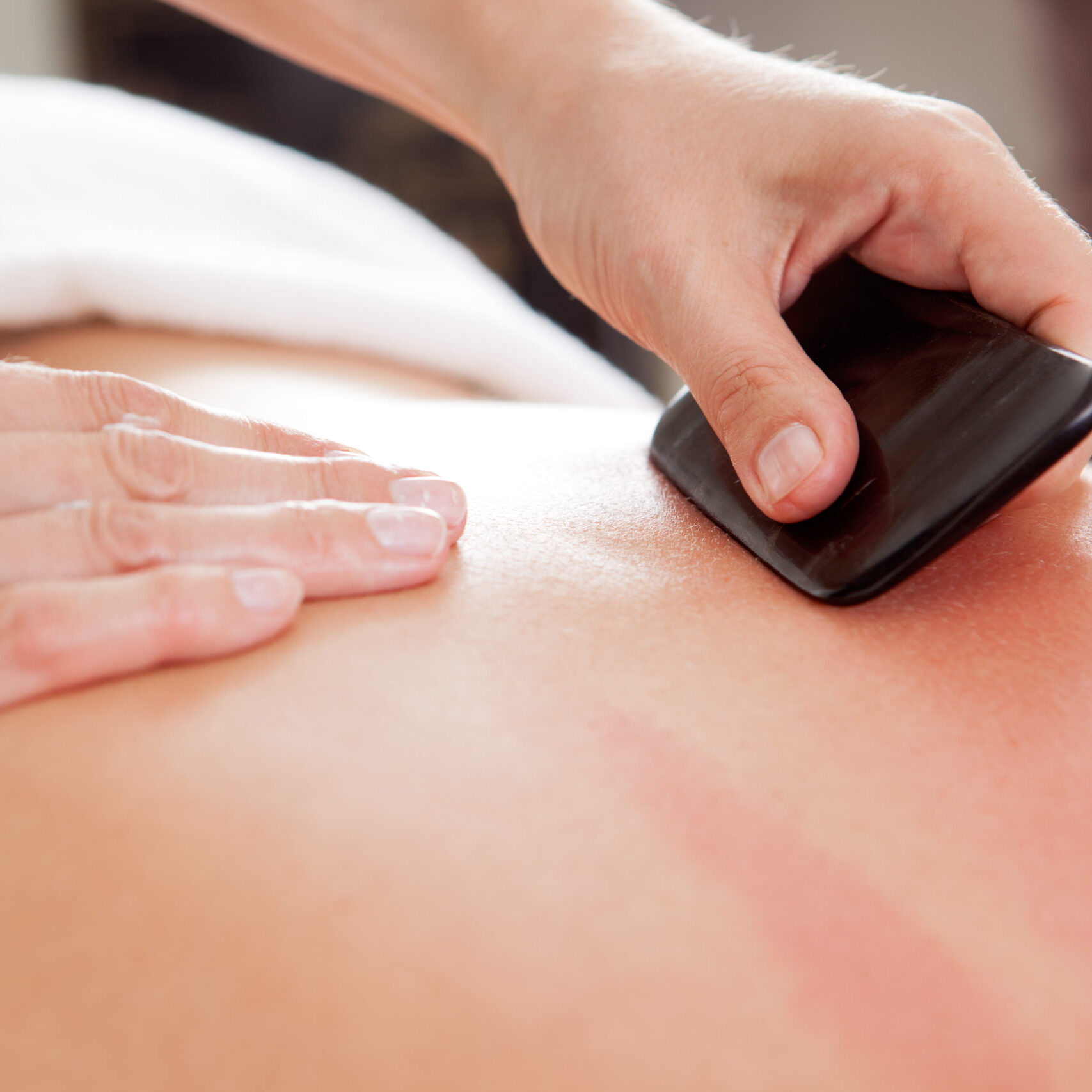 Large bone scraper tool being used ruing a guasha acupuncture treatment
